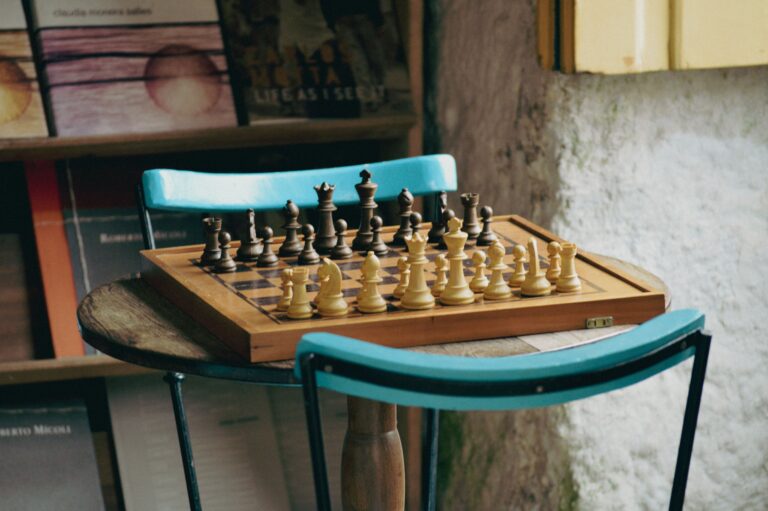 Chessboard with pieces set for play on a wooden table in a cozy rustic indoor setting.